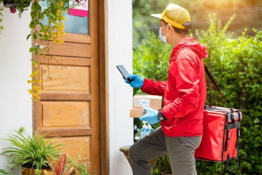 delivery-man-wearing-blue-gloves-red-jacket-searching-customer-address-by-mobile-phone_43157-1214